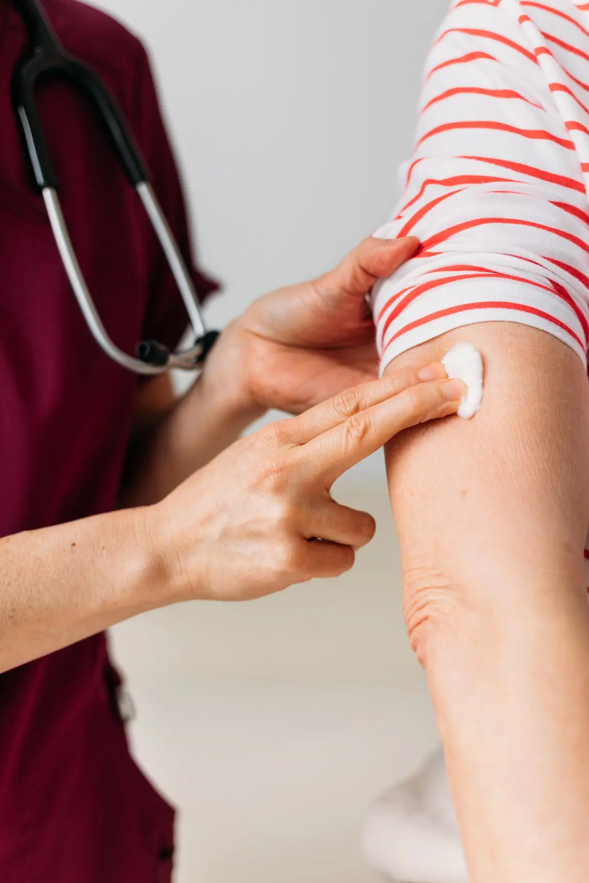 nurse applying pressure to patient's arm with a cotton ball