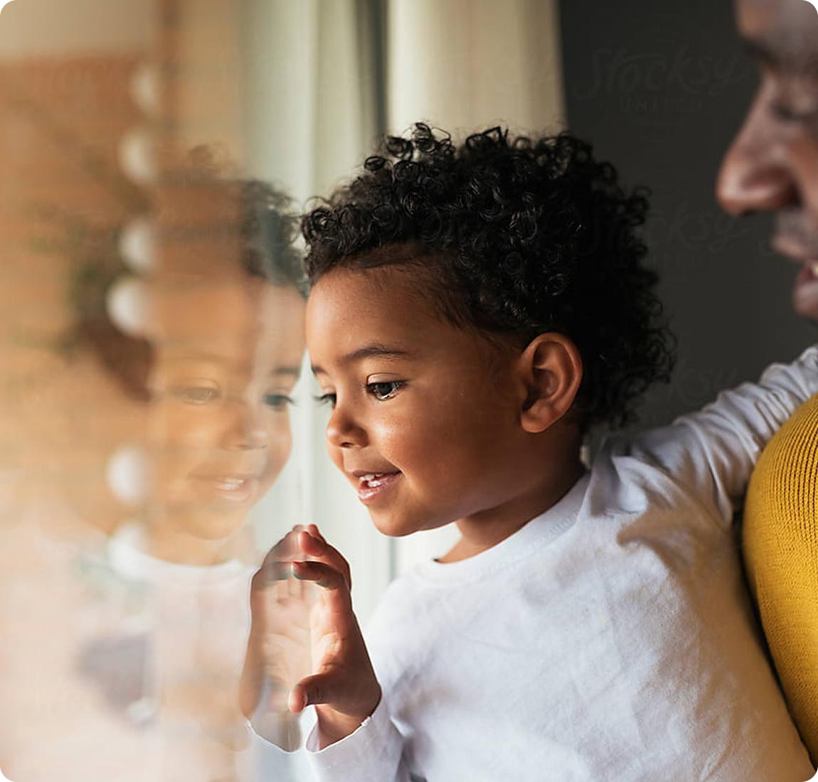 toddler being held by adult and looking out a window