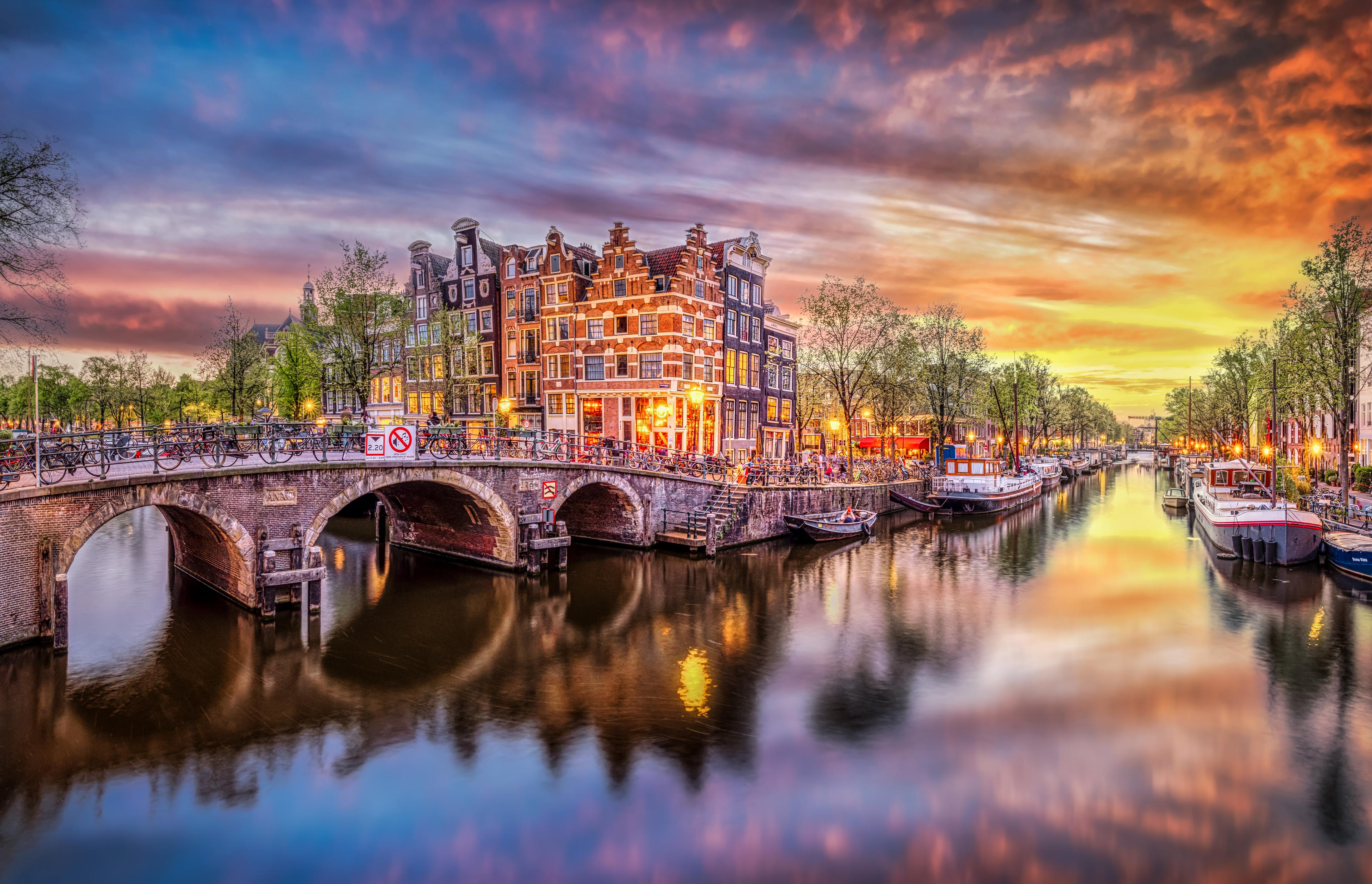 Panoramic photo of the historic city center of Amsterdam along a river at sunset