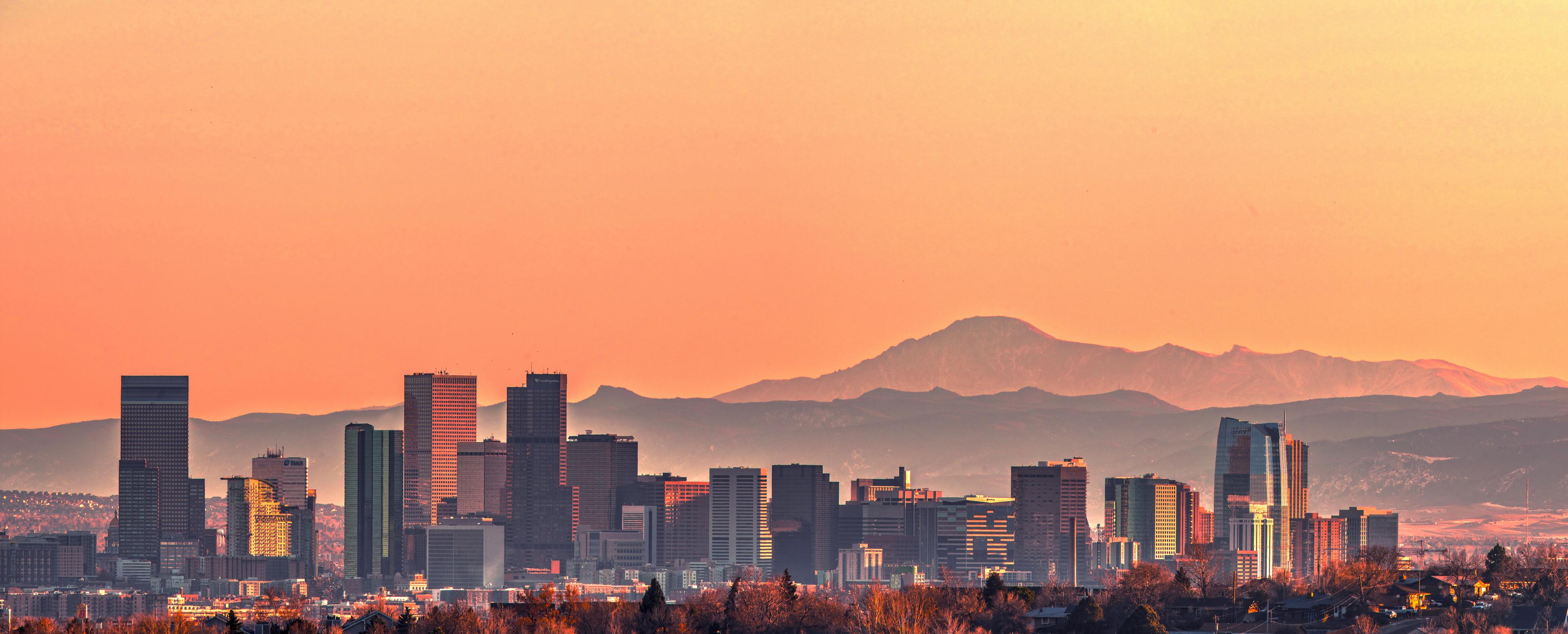 Denver skyline with mountains in the background during sunset