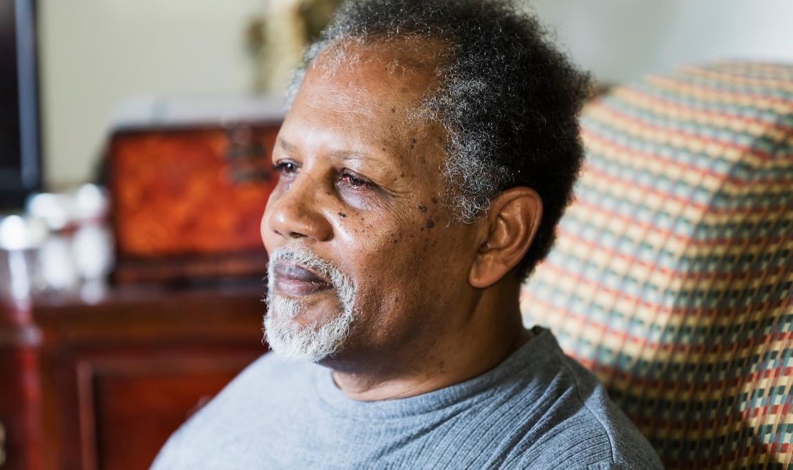 Older man sitting in chair with neutral expression