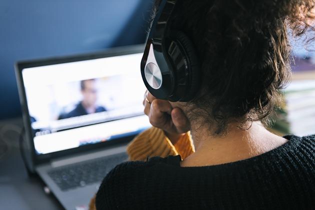 woman wearing headphones and watching a video on a laptop